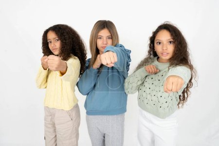 Téléchargez les photos : Trois jeunes belles jeunes filles multiraciales Poing de poing pour se battre, attaque agressive et en colère, menace et violence - en image libre de droit