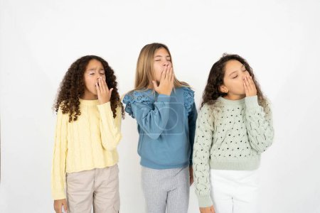 Photo for Three young beautiful multiracial kid girls being tired and yawning after spending all day at work. - Royalty Free Image