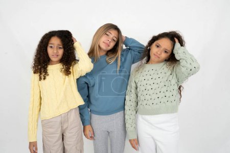 Photo for Three young beautiful multiracial kid girls being confused and wonders about something. Holding hand on head, uncertain with doubt. Pensive concept. - Royalty Free Image