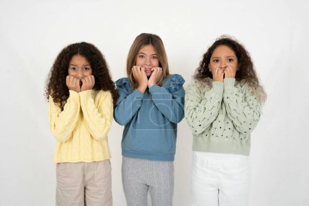 Fearful Three young beautiful multiracial kid girls keeps hands near mouth, feels frightened and scared,  has a phobia,  Shock and frighted concept.