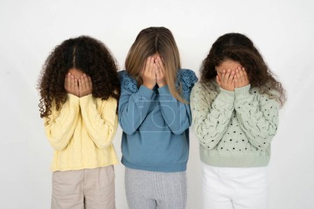 Téléchargez les photos : Trois jeunes belles jeunes filles multiraciales couvrant ses visages de ses mains, étant dévastées et pleurant. Triste concept - en image libre de droit