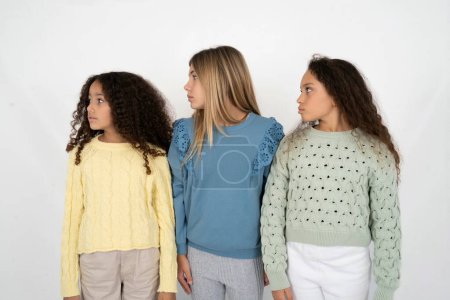Foto de De cerca foto de perfil lateral Tres chicas jóvenes hermosas multirraciales niño no sonriendo atento escuchar concentrado - Imagen libre de derechos