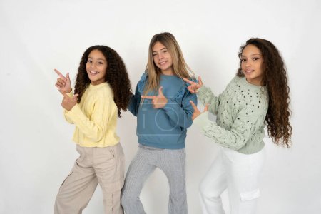 Foto de Tres jóvenes hermosas niñas multirraciales apuntan al copyspace recomiendan descuentos de ventas - Imagen libre de derechos