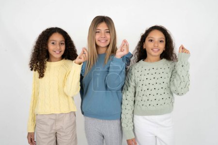 Photo for Three young beautiful multiracial kid girls pointing up with hand showing up seven fingers gesture in Chinese sign language Q. - Royalty Free Image