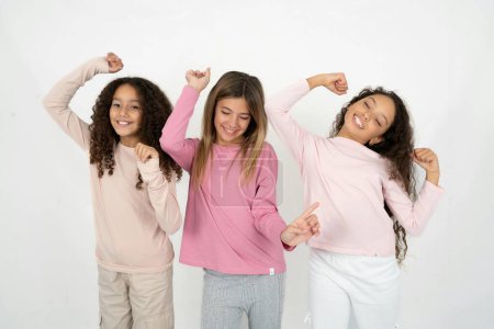 Téléchargez les photos : Photo de optimiste Trois jeunes belles filles multiraciales ont du plaisir et danse vêtements insouciants être d'humeur parfaite fait des mouvements. Passe du temps libre sur disco partie - en image libre de droit