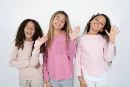 Téléchargez les photos : Succès réjoui Trois jeunes belles filles multiraciales lèvent la paume et ferment les yeux dans la joie d'être divertis par des amis - en image libre de droit