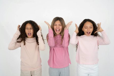 Foto de Tres chicas jóvenes hermosas y multirraciales se vuelven locas mientras la cabeza gira se siente estresada debido a una situación horrible. - Imagen libre de derechos