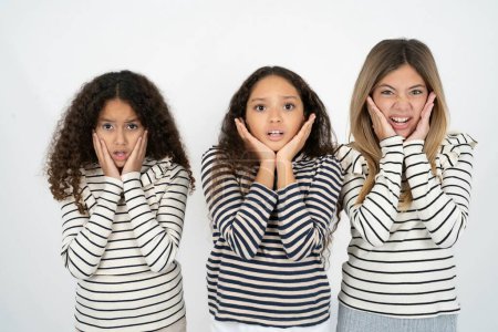 Téléchargez les photos : Bouleversé trois jeunes belles filles multiraciales enfant toucher le visage avec deux mains - en image libre de droit