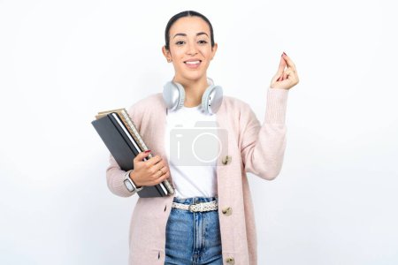 Photo for Beautiful arab woman student carries notebooks over white background pointing up with hand showing up seven fingers gesture in Chinese sign language Q. - Royalty Free Image
