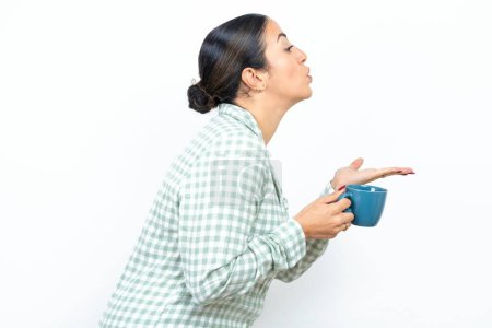 Téléchargez les photos : Profil vue de côté, portrait d'attrayant Belle jeune femme portant pyjama à carreaux vert et tenant une tasse envoyant baiser l'air - en image libre de droit