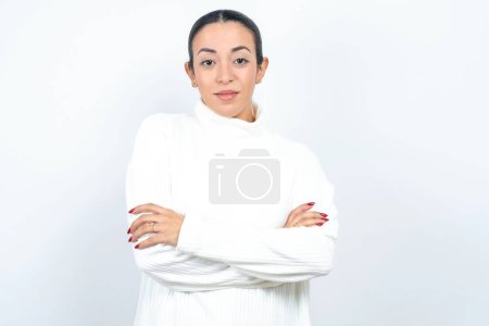 Foto de Mujer árabe hermosa confiada posando sobre fondo blanco con los brazos cruzados mirando a la cámara - Imagen libre de derechos