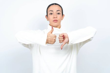 Photo for Beautiful arab woman posing over white background showing thumb up down sign - Royalty Free Image