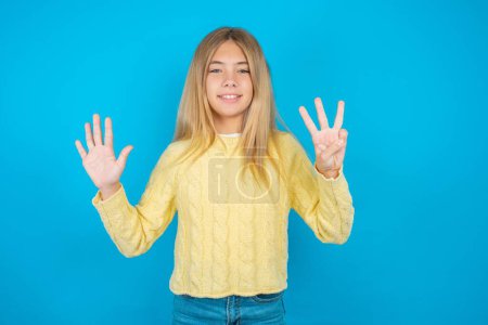 Téléchargez les photos : Belle fille enfant portant un pull jaune montrant et pointant vers le haut avec les doigts numéro huit tout en souriant confiant et heureux. - en image libre de droit