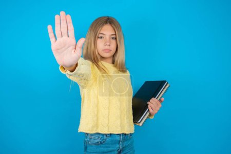 Photo for Beautiful kid girl wearing yellow sweater doing stop sing with palm of the hand. Warning expression with negative and serious gesture on the face. - Royalty Free Image