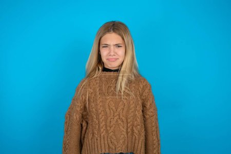 Photo for Offended dissatisfied Beautiful kid girl wearing brown knitted sweater with moody displeased expression at camera being disappointed by something - Royalty Free Image