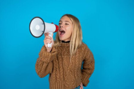 Photo for Funny Beautiful kid girl wearing brown knitted sweater People sincere emotions lifestyle concept. Mock up copy space. Screaming in megaphone. - Royalty Free Image