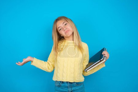 Photo for Careless attractive Beautiful kid girl wearing yellow sweater shrugging shoulders, oops. - Royalty Free Image