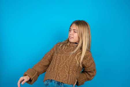 Foto de Hermosa niña usando suéter de punto marrón tiene dolor de espalda - Imagen libre de derechos