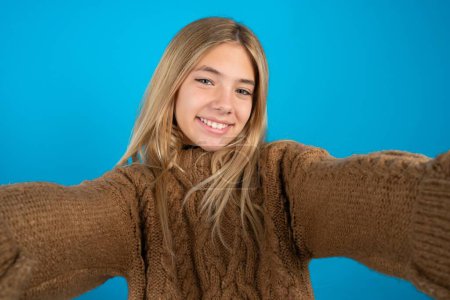 Téléchargez les photos : Photo de Belle gamine portant un pull marron tricoté faire selfie - en image libre de droit