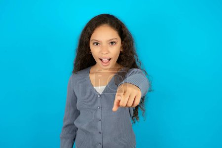 Photo for Beautiful kid girl wearing casual jacket over blue background pointing displeased and frustrated to the camera, angry and furious ready to fight with you. - Royalty Free Image