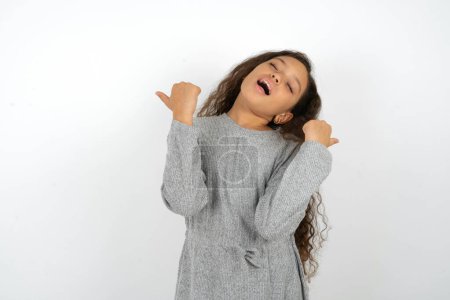 Foto de Extático hermosa adolescente chica usando gris vestido sobre blanco fondo gritar fuerte sí puño hasta levantar ganar lotería - Imagen libre de derechos