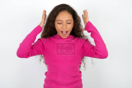 Photo for Beautiful kid girl wearing pink turtleneck over white background goes crazy as head goes around feels stressed because of horrible situation - Royalty Free Image