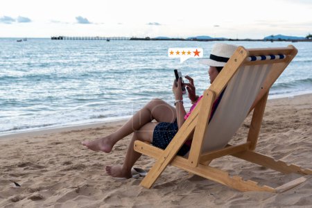 Téléchargez les photos : Jeune asiatique heureuse femme en utilisant smartphone sur la plage, service à la clientèle et cinq étoiles cote de satisfaction - en image libre de droit