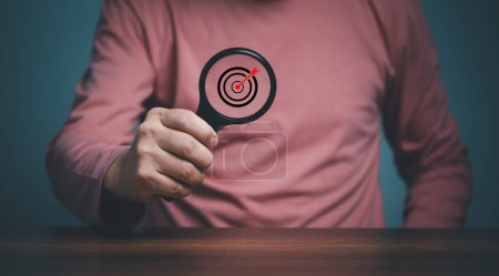 Photo for Target  inside magnifier glass for focus business objective, hand of person holding magnifier glass with goal target, Search, goal, strategy, success. - Royalty Free Image