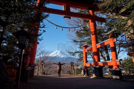 Photo for Travel Japan on winter, Woman raised hands with a giant torii gate or Red pole and fuji mountains. - Royalty Free Image