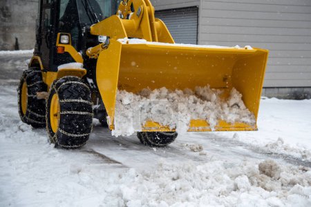 Foto de Tractor cucharada con nieve en el invierno, Limpiar la nieve después de una tormenta. - Imagen libre de derechos