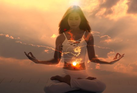 Young spiritual meditation aura woman with her eyes closed feeling free on nature energy at sunrise.