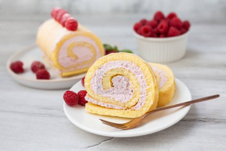 Tasty roll cake, sponge roll, Swiss roll stuffed with cream cheese ,decorated with fresh raspberries. Homemade cake. 
