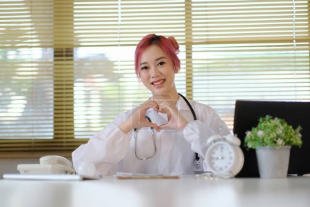 Téléchargez les photos : Médecin féminin forme un cœur avec ses mains au travail - en image libre de droit