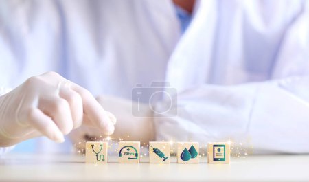 Foto de Doctor arranging and stacking wooden block cubes with printed screen health care and medical icons for the concept of health and wellness. Hand-arranging a wood block with a medical icons. - Imagen libre de derechos