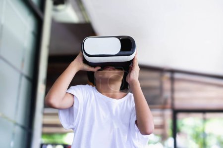 Téléchargez les photos : Jeune fille enfant jouer jeu de réalité virtuelle tenir vr lunettes et surpris. Cyber espace et jeux virtuels - en image libre de droit