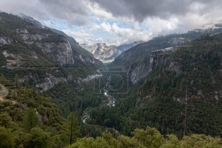 Téléchargez les photos : Vallée dans le parc national Yosemeti avec des conifères, nuages bas, ciel nuageux et taches de brouillard, Californie, États-Unis - en image libre de droit