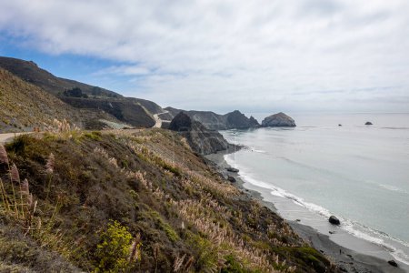 Téléchargez les photos : La belle côte ouest de la Californie le long de l'autoroute 1, avec des prairies et des rochers, un ciel bleu et la mer, avec les restes de brouillard au loin - en image libre de droit