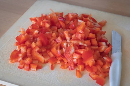 Foto de Pimiento rojo en rodajas en cubos pequeños en una tabla de cortar, listo para ser incorporado en una comida - Imagen libre de derechos