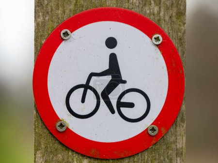 A ROUND PROHIBITION SIGN FOR CYCLING IN RED AND WHITE, PLACED ON A WOODEN POST, THE NETHERLANDS