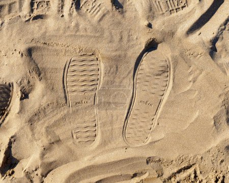 Photo for Rimini, Italy - October 18, 2020: Footprints in the sand with Hogan shoes. Advertising idea to make your mark. Hogan is an Italian brand producing shoes, bags and outerwear, born in 1986. - Royalty Free Image
