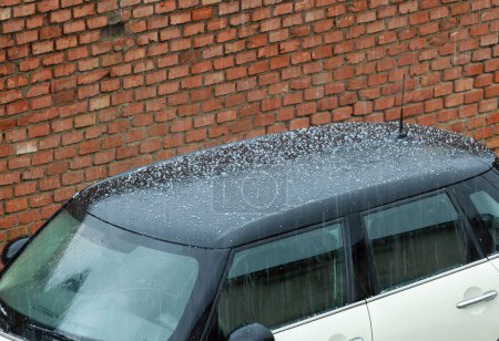 Foto de Hail falling over car roof. Hailstones can damage the bodywork. - Imagen libre de derechos