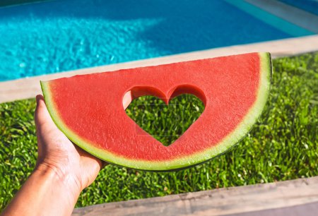 Photo for Slice of watermelon with heart and without seeds in the pool in summer. - Royalty Free Image