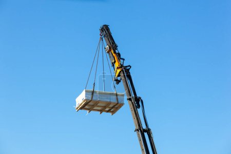 Photo for Crane moves large electrical component for radio wave repeater. - Royalty Free Image
