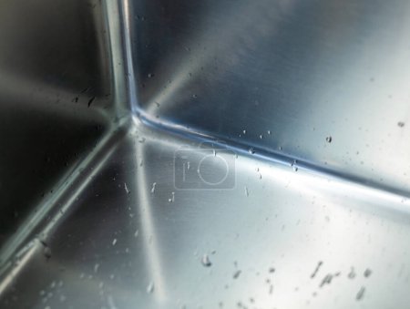 Téléchargez les photos : Détail avec mise au point sélective dans le coin d'un évier en acier inoxydable avec gouttes d'eau. - en image libre de droit