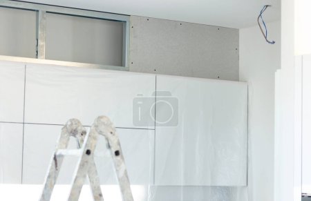 Téléchargez les photos : Fermeture en placoplâtre de l'espace entre les armoires de cuisine et le plafond. - en image libre de droit
