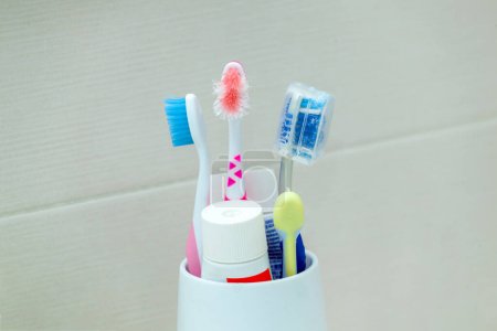 Foto de Cepillos de dientes usados y arruinados en un soporte blanco sobre un fondo neutro. - Imagen libre de derechos