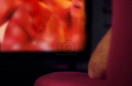 Téléchargez les photos : Un homme assis le dos tourné sur un canapé regardant un film X. - en image libre de droit