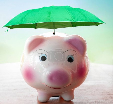 Foto de Financial security concept, pink piggy bank is protected by a  umbrella. - Imagen libre de derechos