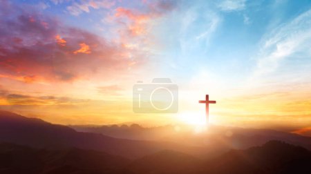 Le symbole crucifix de Jésus sur le fond du ciel couchant de la montagne