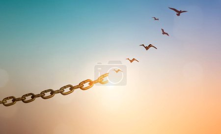 Silhouettes of broken chain and birds flying in sky-stock-photo